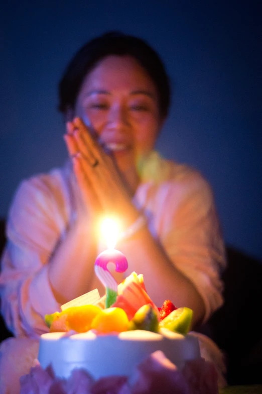 a woman is clapping in front of her birthday cake