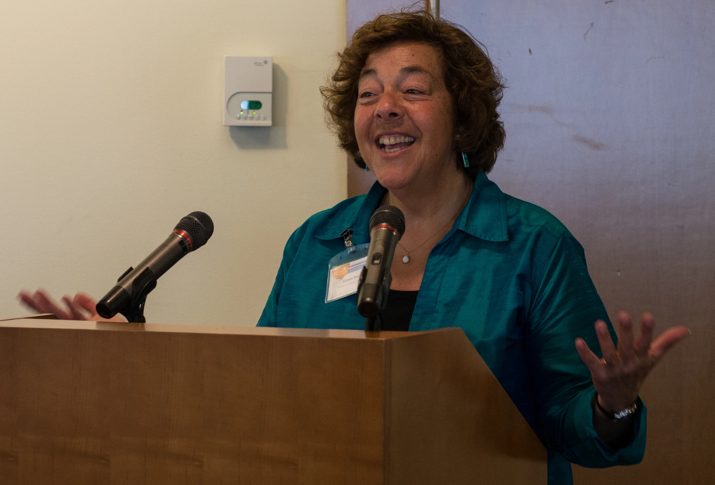 a woman smiling at a podium with a microphone