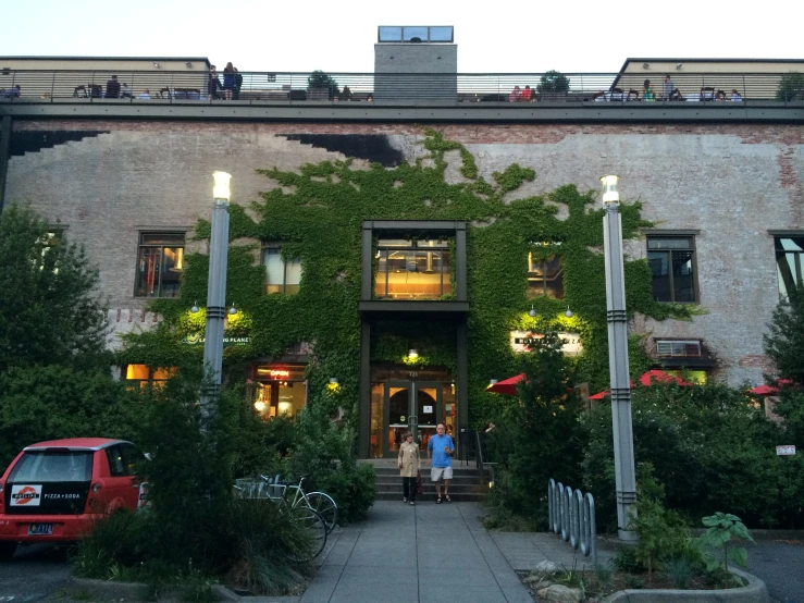 a building with vines covering the facade and a couple walking up it