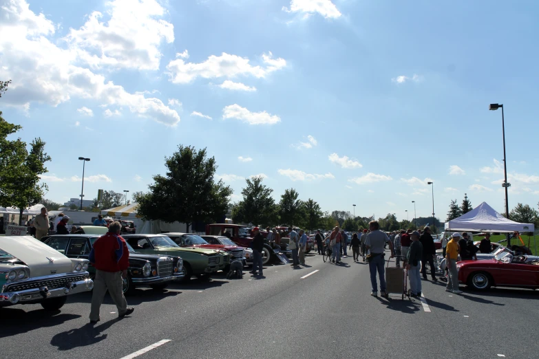 some people are walking around in front of some vintage cars