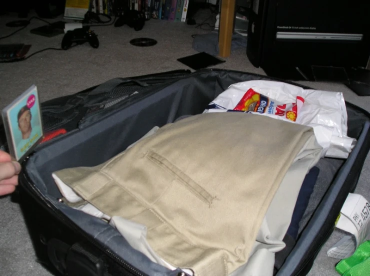 a person opening an open luggage bag that has clothes inside of it