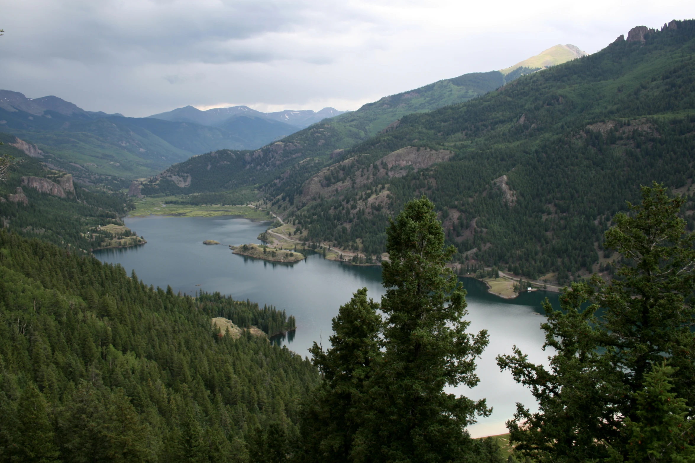 a lake in a forest next to mountains with trees