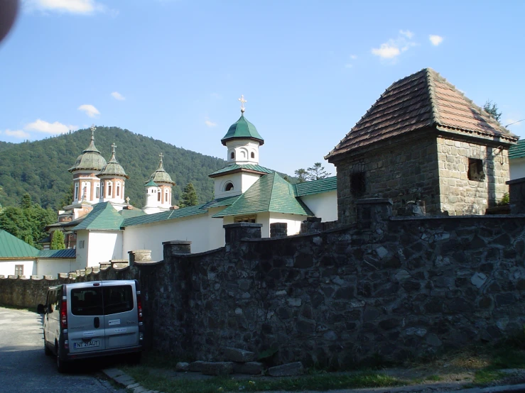 a white van parked next to a rock wall with a green roofed roof