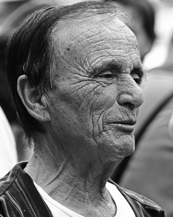 an older man looking into the distance while wearing a vest