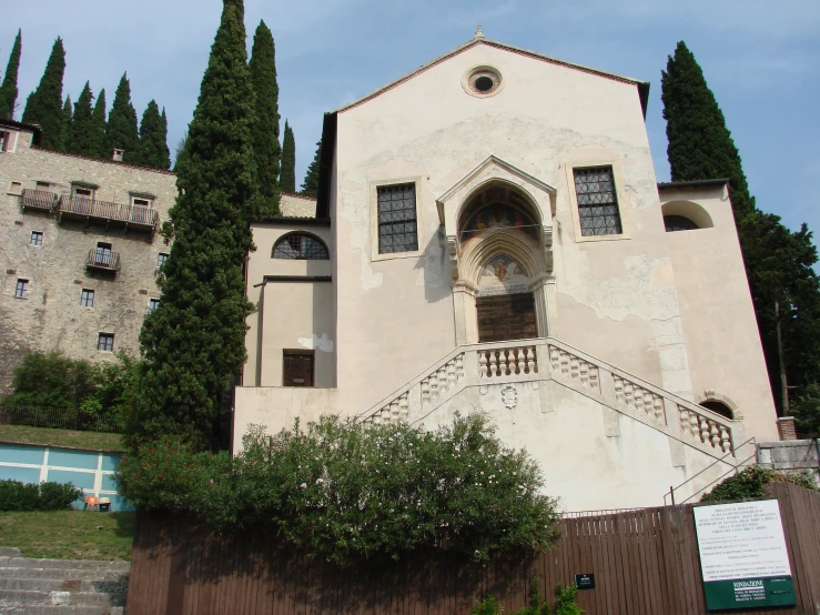 a stone church with lots of windows sits next to a tree lined sidewalk