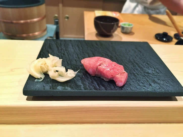 a chopping board with meat, onion and garlic on it