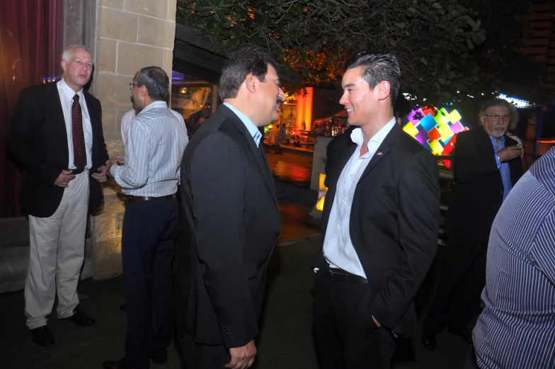 two men in suits stand together in a crowd