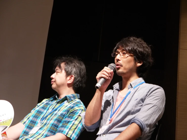 two young men sitting down with microphones in their hands