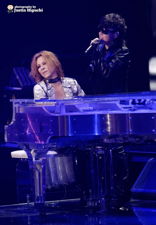 a woman sitting at a piano as a man stands behind her