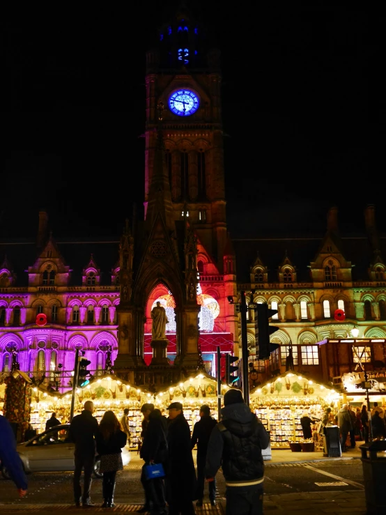 several people stand near a street lit up with christmas lights