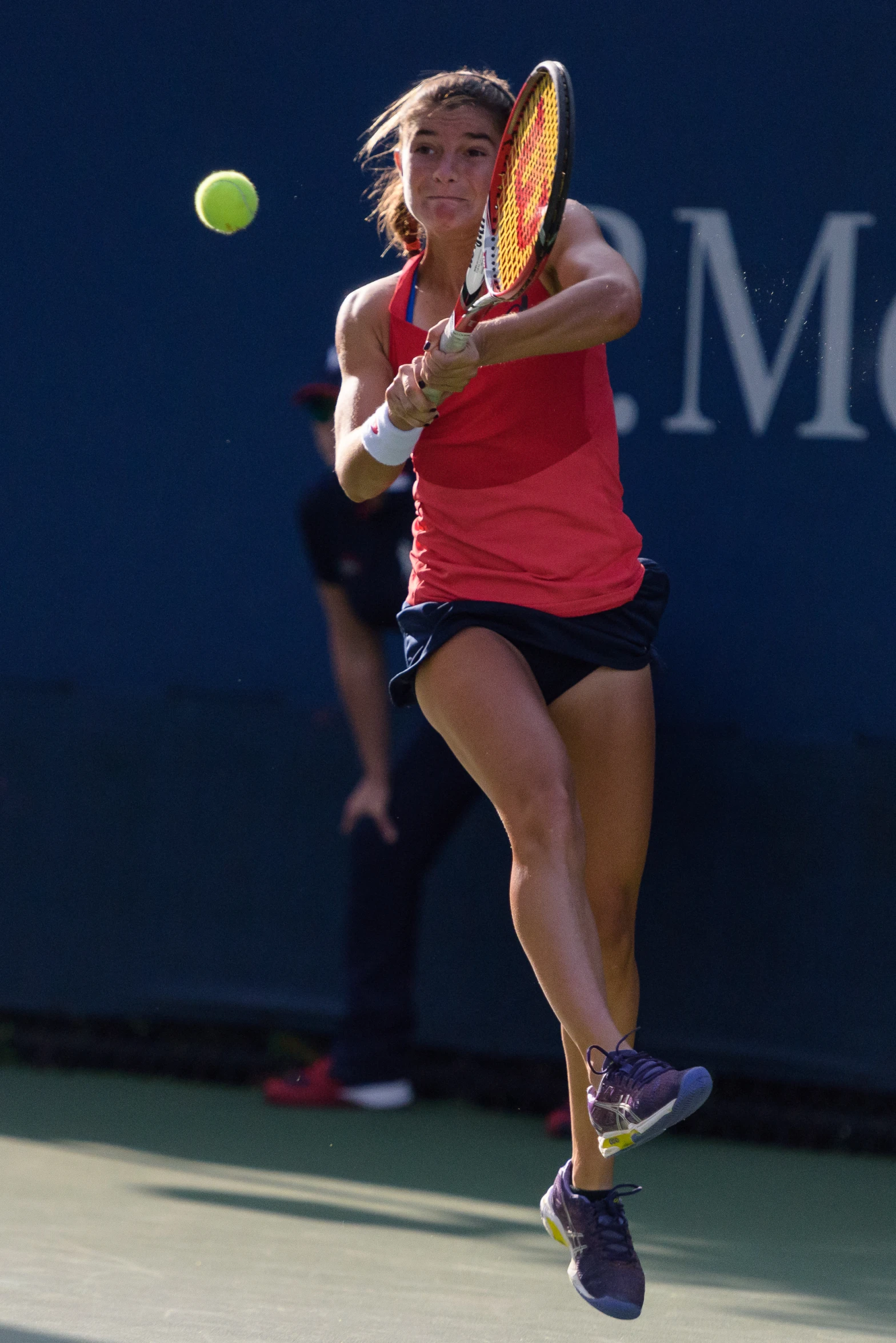 a tennis player jumping to return the ball with her racket