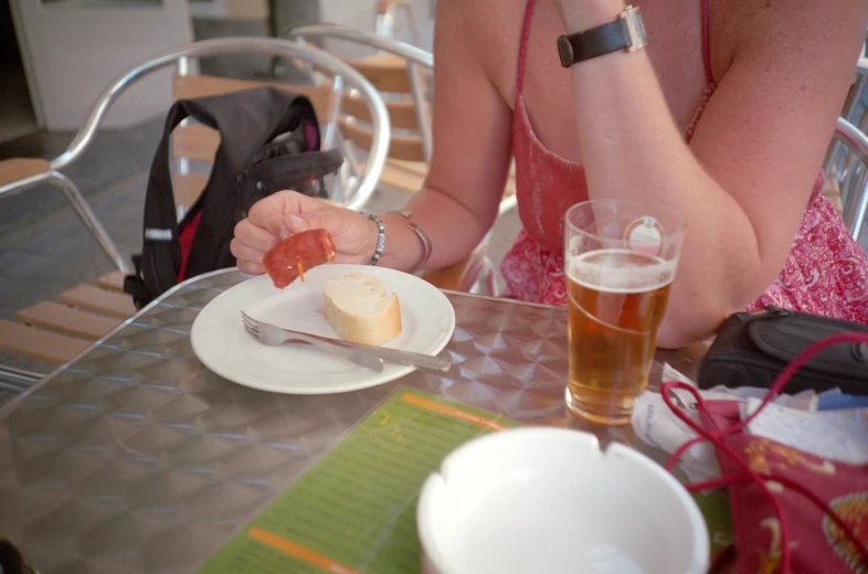 a girl is eating pizza at an outdoor table with beer