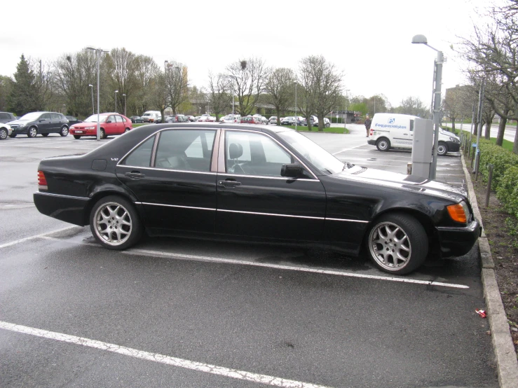 a black car in a parking space with some people