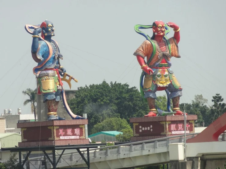 two big statue statues next to each other near a bridge