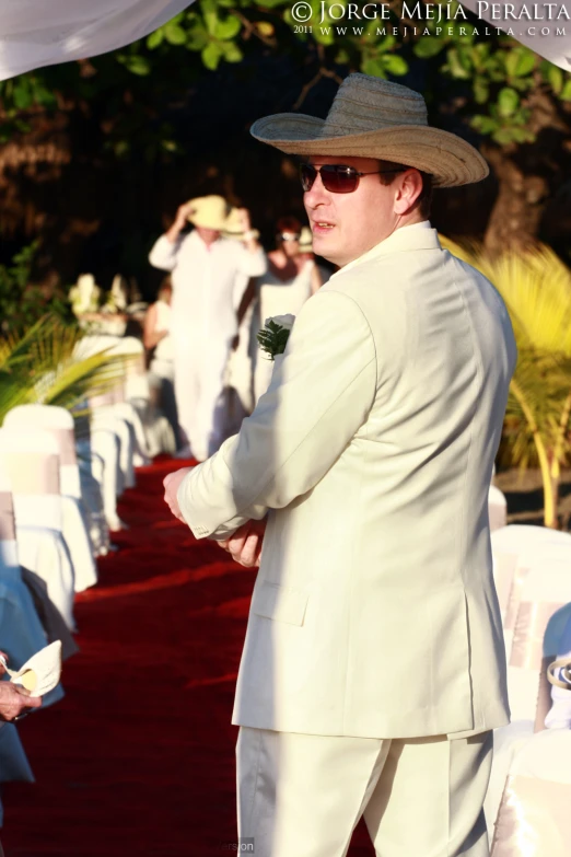 the man is wearing white clothes and has on a hat