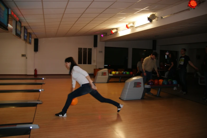 a young person is throwing an orange ball on bowling