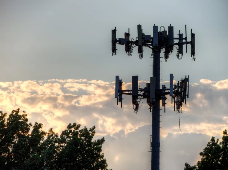 a large tv tower surrounded by trees and clouds