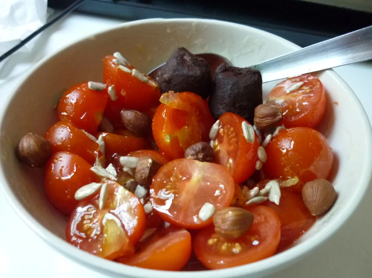a bowl filled with sliced tomatoes, nuts and chocolate
