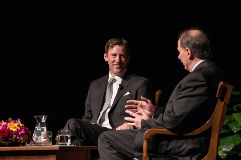 two men at a table are talking with each other