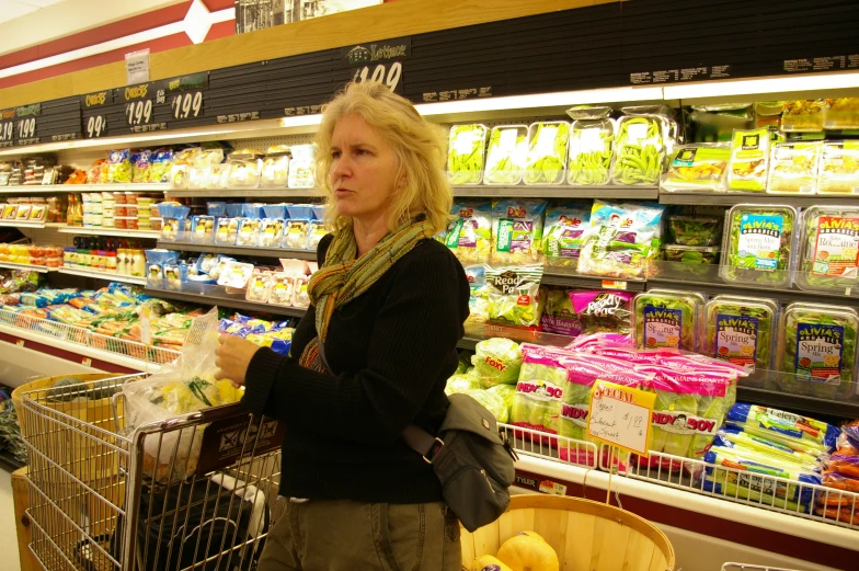 there is a woman standing at the supermarket with her grocery cart