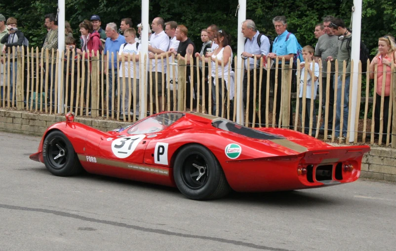 an antique race car sits in front of a crowd