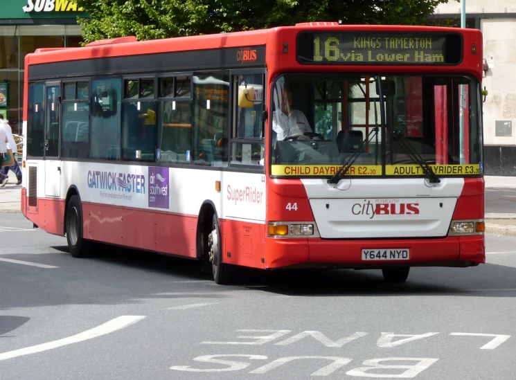 an orange and white bus driving down a street