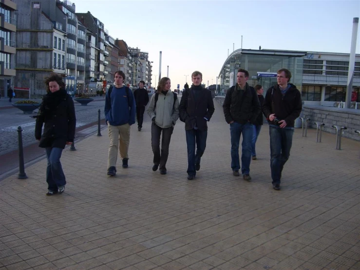 a group of young men walk down a paved sidewalk