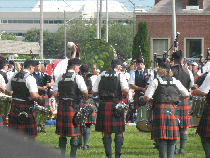 men in kilts playing with an instrument at a scottish parade