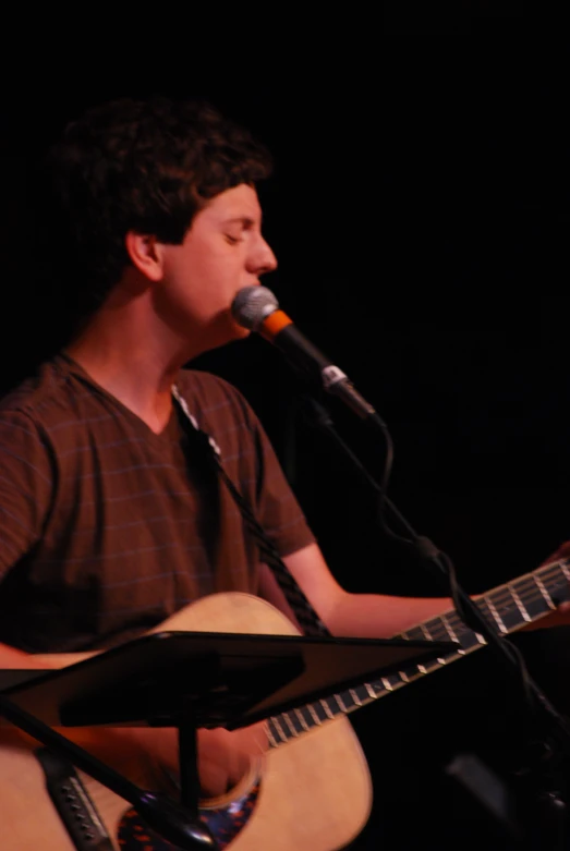 a man playing a guitar in front of a microphone