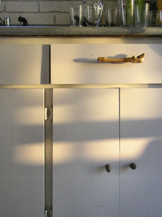 the kitchen cabinet door is partially open with a bunch of items around it