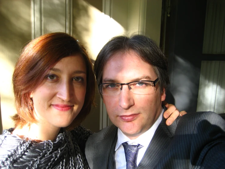 a man with glasses next to a woman in suit