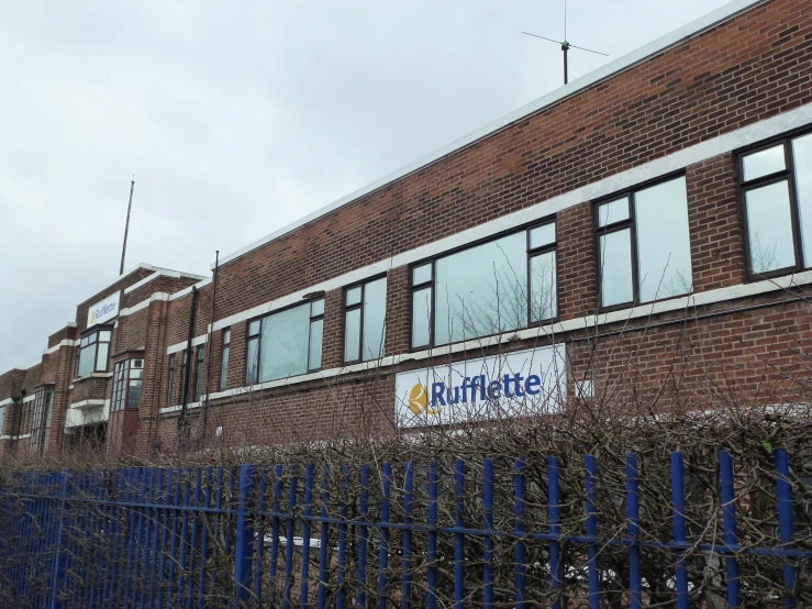 a red brick building with an arched window and blue fence