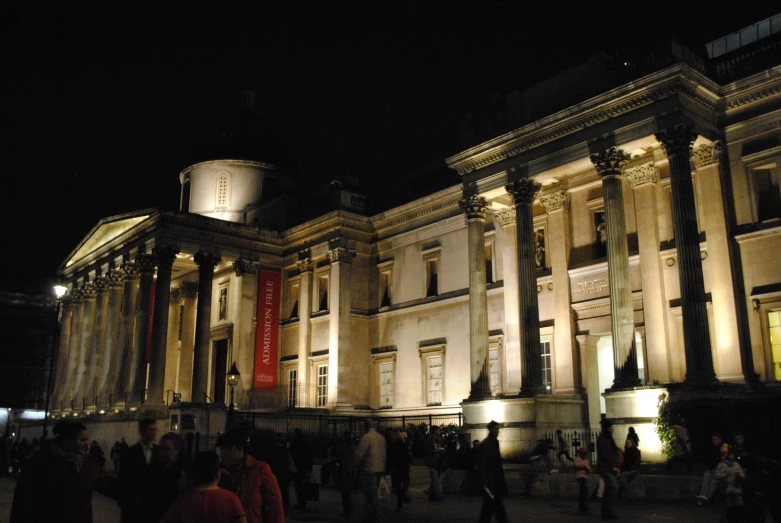 people walking in front of an old building at night