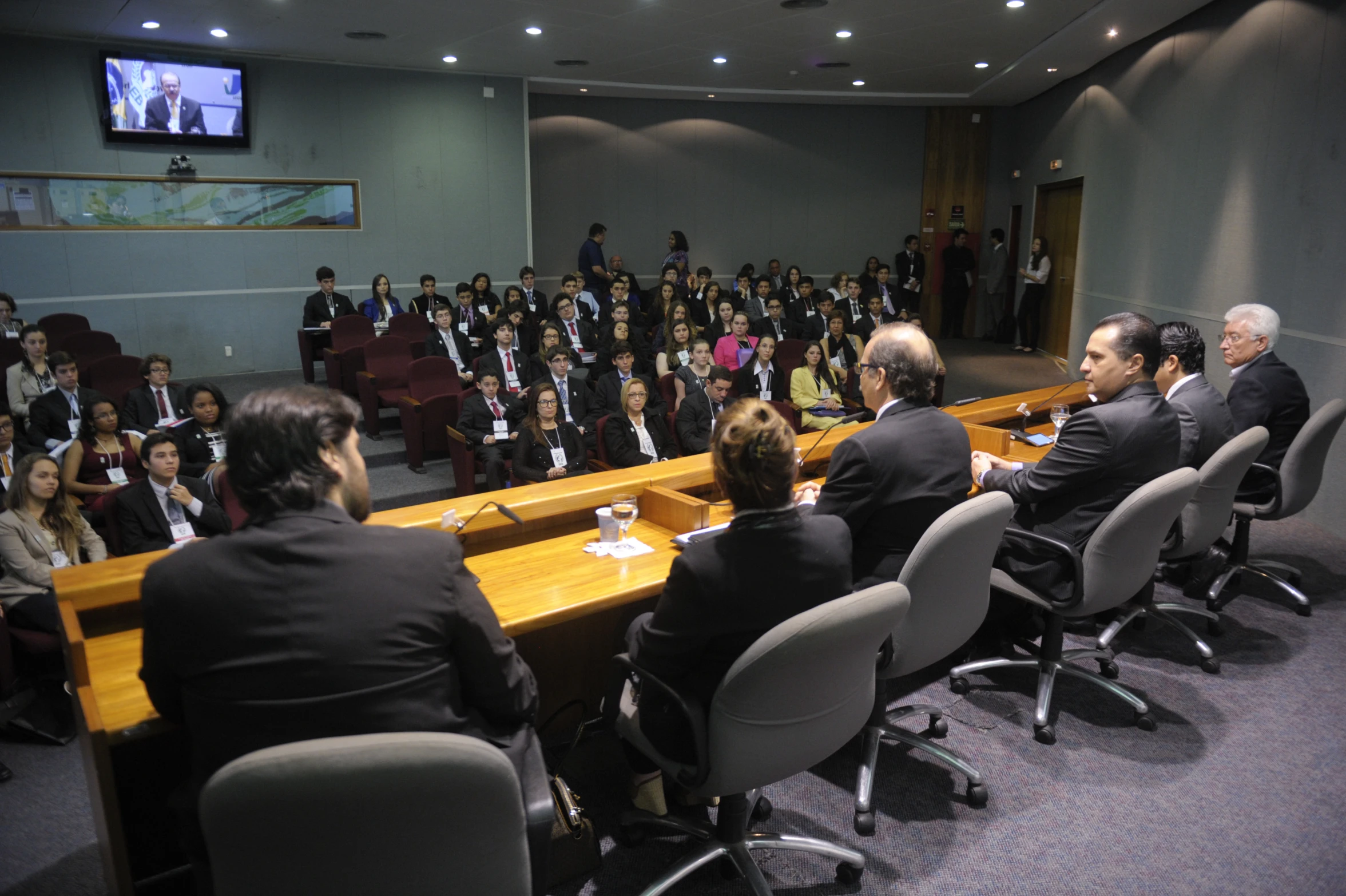 a conference of business people in suits sitting at desks