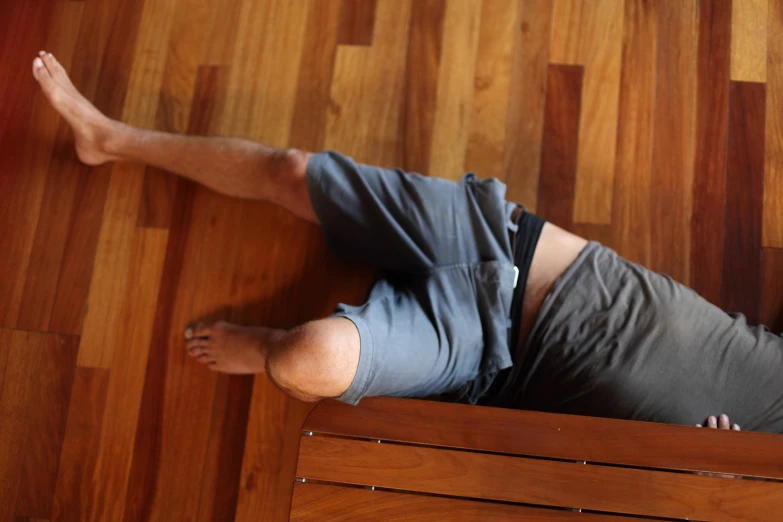 a man wearing grey sitting on a bench in a room