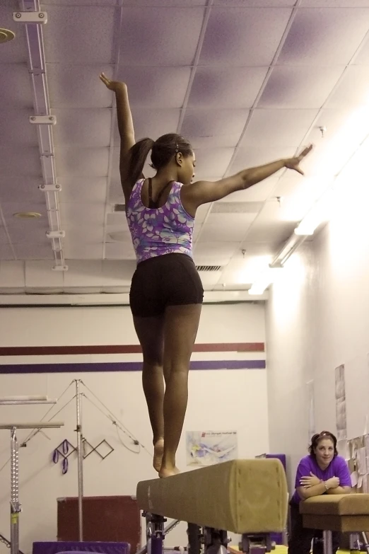 a woman is standing on a beam while wearing purple shirt