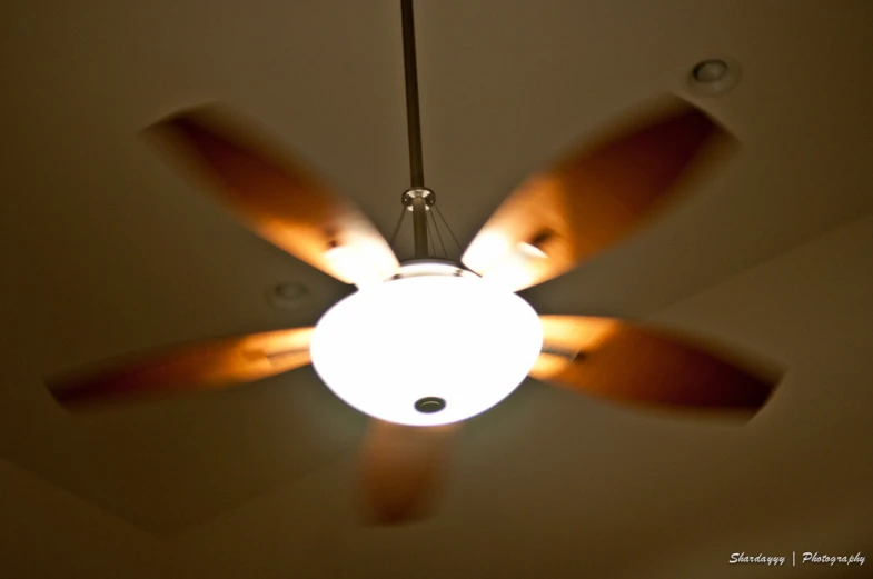 a ceiling fan is lit from the top of it