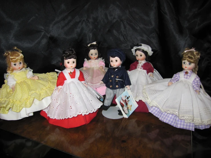 a group of dolls wearing gowns and tiara on a table
