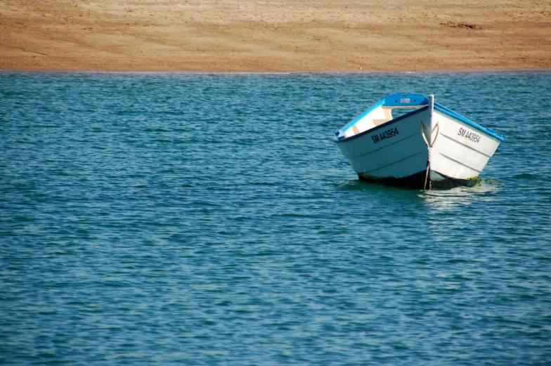 a small boat on the water next to a sandy beach