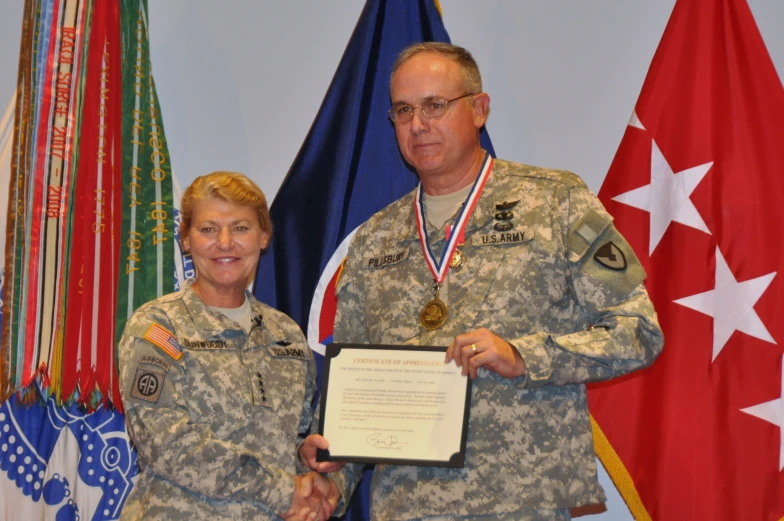 man and woman in uniform standing next to flags