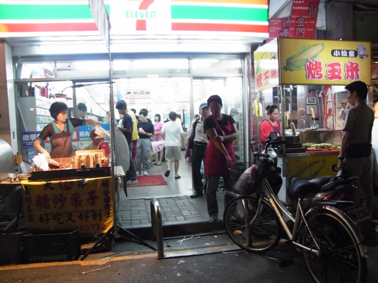 a group of people standing around outside of a convenience store