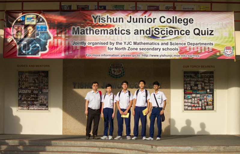 a group of school boys wearing suspenders and backpacks are posing in front of a banner in a classroom building