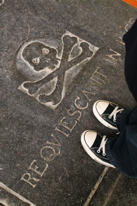 feet standing on the sidewalk while writing with chalk