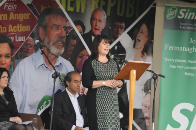 woman speaking at podium during speech on stage with pictures on wall