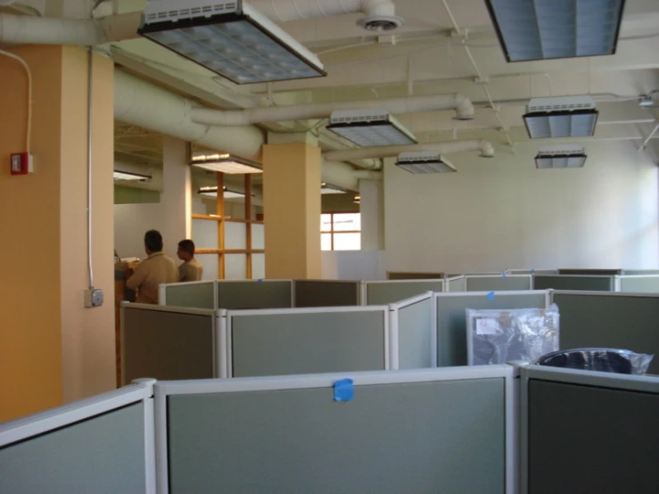 people are sitting and standing in an office cubicle