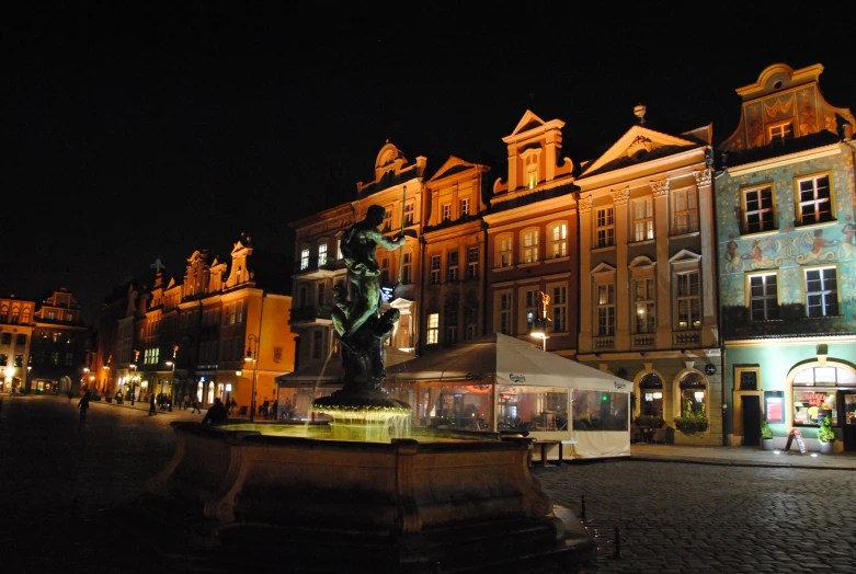 the city square in front of buildings with statues and lights