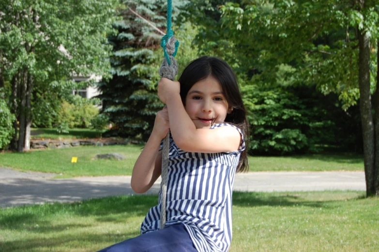 a girl sitting on a swing in a park