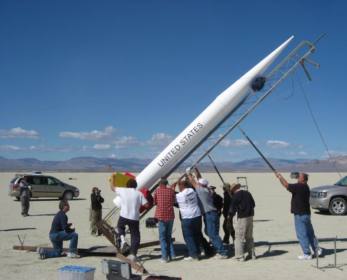 a group of people are posing for a picture with an upside down kite