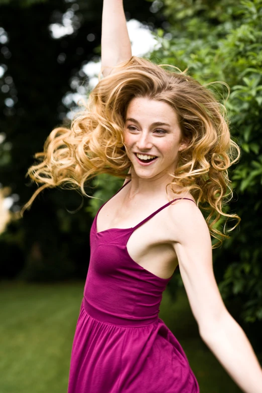 a smiling girl in a purple dress with hair blowing