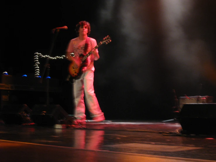 a man with a guitar standing in front of a microphone